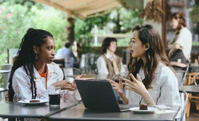 Two work colleagues meeting at a cafe, one of whom is wearing LinkBuds Open earbuds.