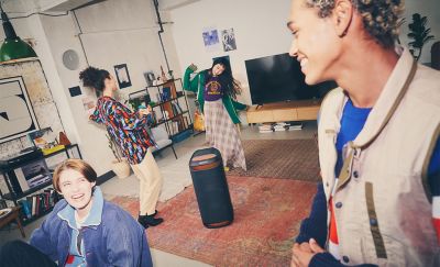 Image of four people in a living room dancing around the SRS-XV800 speaker with red ambient lighting 