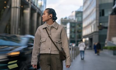 Image of a person on a busy street wearing the WF-1000XM5 headphones