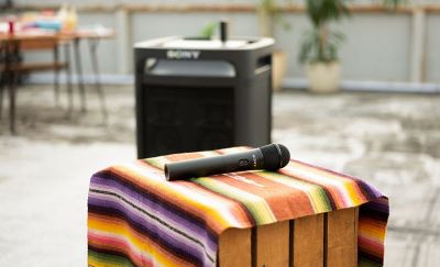 Un micrófono ULT encima de una manta y una caja. En el fondo hay un parlante ULT Tower