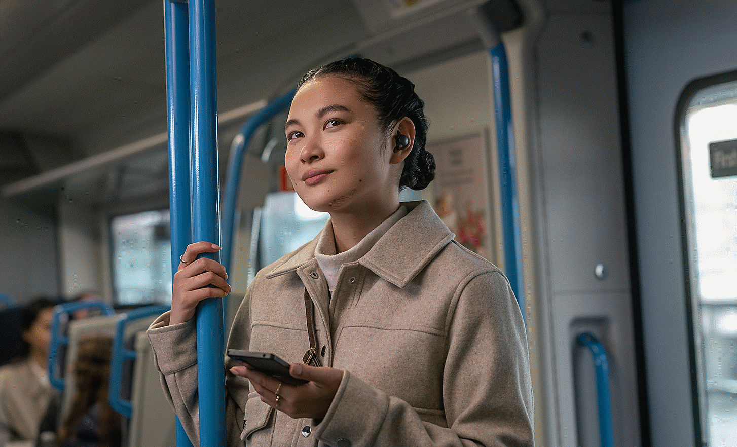 Imagem de uma pessoa num comboio a usar os auriculares WF-1000XM5