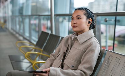 Image of a person on a train platform wearing the WF-1000XM5 headphones