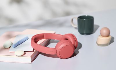Bezdrátová sluchátka Sony WH-CH530 korálové barvy na stole ve slunečním světle