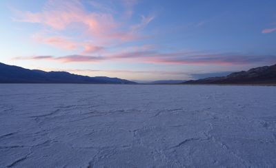 Wide-angle shot of desert landscape with sunset behind distant mountains