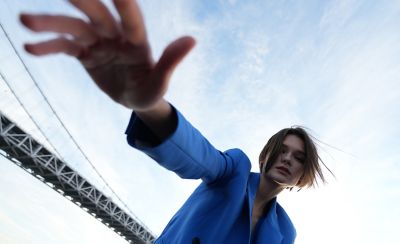 Wide-angle portrait of woman with part of suspension bridge span in background