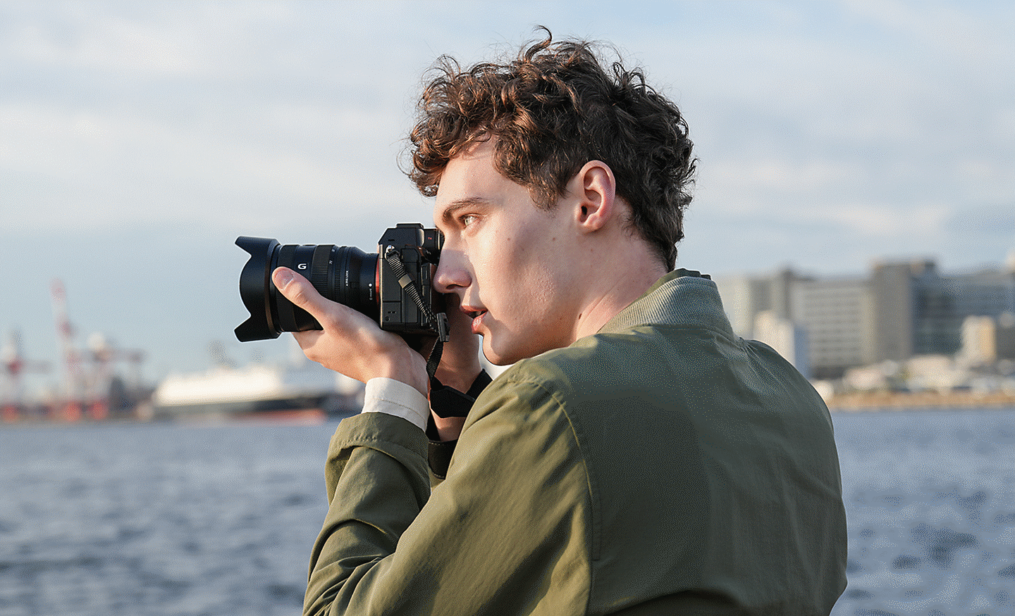 Човек снима на крайбрежие с фотоапарат в ръка и използва визьор
