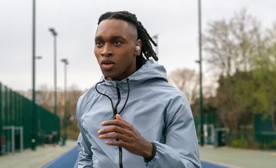 Image of a person running on a track whilst wearing the WF-1000XM5 headphones