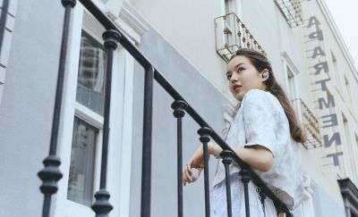 A young woman wearing a pair of LinkBuds Open earbuds leaning on a railing.