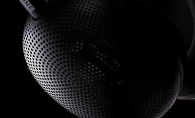 Primer plano de unos audífonos tipo diadema negros sobre un fondo negro