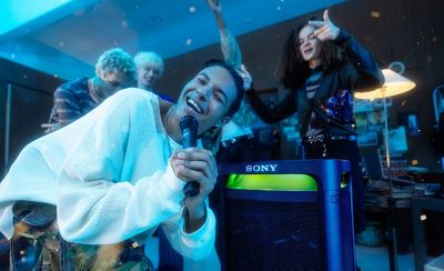 Una persona cantando con el ULTMIC1 inclinada frente al parlante TOWER 9