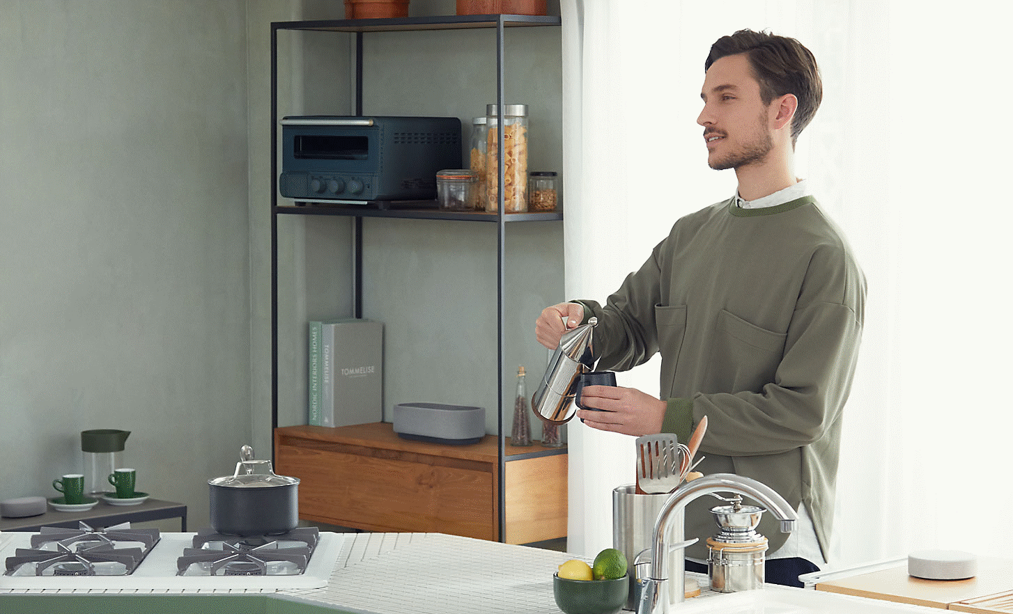 Slika osobe koja poslužuje kavu u kuhinji, okružena je trima zvučnicima sustava HT-AX7
