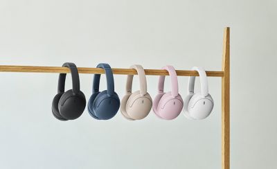 Pětibarevná řada sluchátek Sony WH-CH730N zavěšená na dřevěné kolejnici