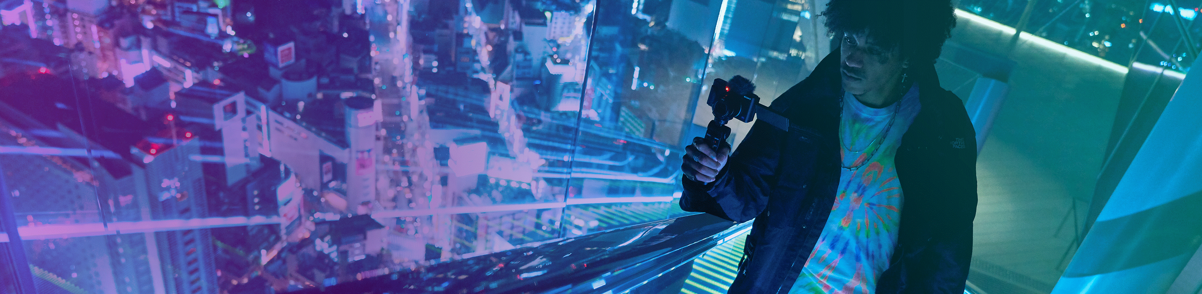 Hombre grabando una vista nocturna en un edificio alto