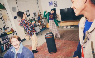 Hình ảnh bốn người đang khiêu vũ trong phòng khách quanh loa SRS-XV800, với ánh sáng xung quanh màu đỏ