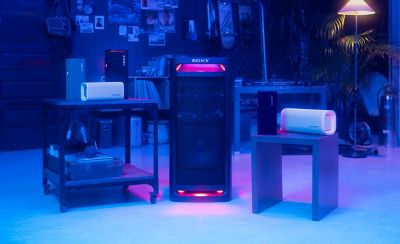 Una sala que muestra la gama de parlantes ULT, con los parlantes ULT FIELD 3 sobre una mesa a la izquierda, el parlante Tower apoyado en el suelo en el medio y el parlante ULT FIELD 5 sobre una mesa a la derecha