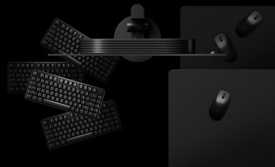 Εναέρια όψη μαύρης οθόνης, βάσης, δύο ποντικιών, ενός mouse pad και 4 πληκτρολογίων σε μαύρο φόντο
