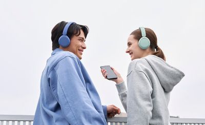 Mladý muž a žena venku s kobaltovými a mátovými bezdrátovými sluchátky Sony WH-CH530