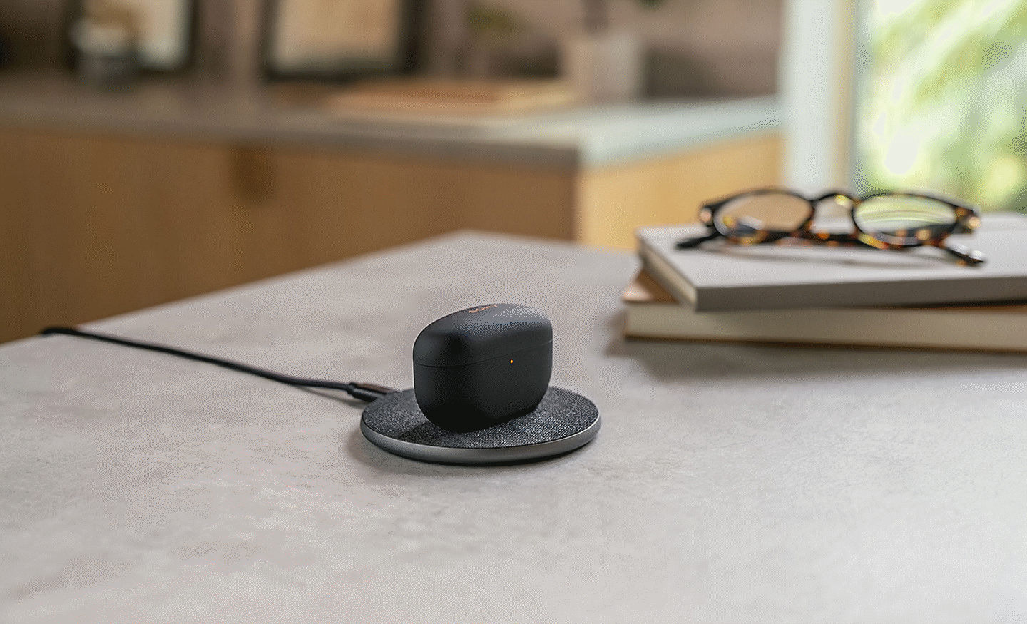 Slika slušalk WF-1000MX5 na brezžični polnilni postaji na vrhu mize