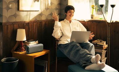 Una persona sentada con una laptop en su regazo hablando con alguien en la pantalla.