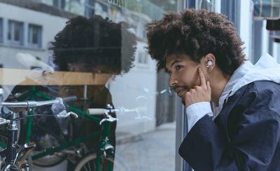 A young man wearing LinkBuds Open earbuds looking through a bicycle shop window.