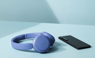 O pereche de căști wireless Sony WH-CH530, modelul cobalt, așezate lângă un smartphone