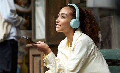 Tânără pe bancă, purtând căști wireless Sony WH-CH530, modelul mentă