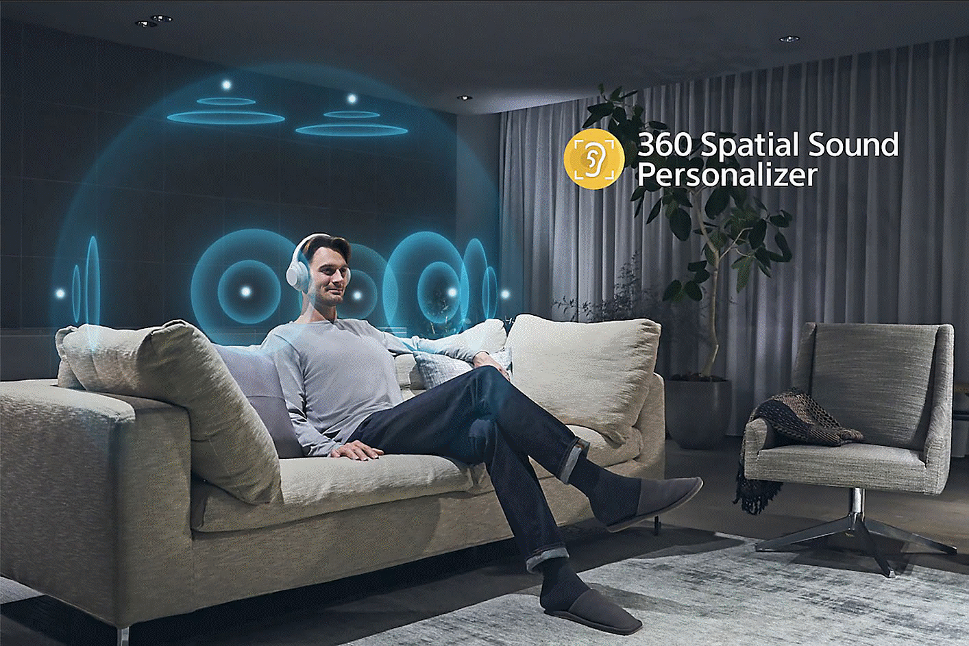Εικόνα ανθρώπου που κάθεται σε καναπέ, φορά ακουστικά και γύρω του υπάρχουν ομόκεντροι κύκλοι και λογότυπο 360 Spatial Sound στα δεξιά