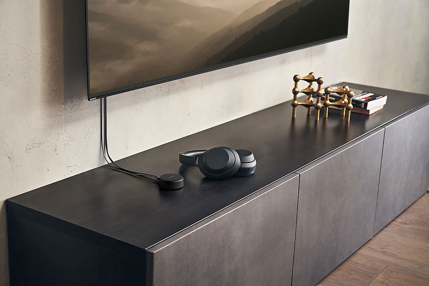 Imagen de audífonos en un mueble para televisor, junto al transmisor inalámbrico Sony WLA-NS7 conectado a un televisor BRAVIA