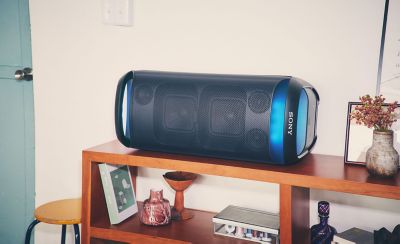 Image of the SRS-XV800 with blue ambient lighting lying horizontally on a bookshelf