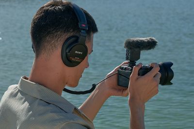 Deniz kenarında mikrofon bir fotoğraf makinesi tutan erkek