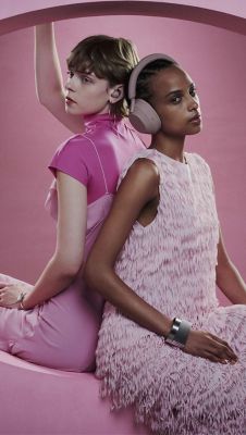 Two women dressed in all pink are sitting on pink monument with her new Smoky Pink WF-1000XM5 and WH-1000XM5 Noise Cancelling Headphones