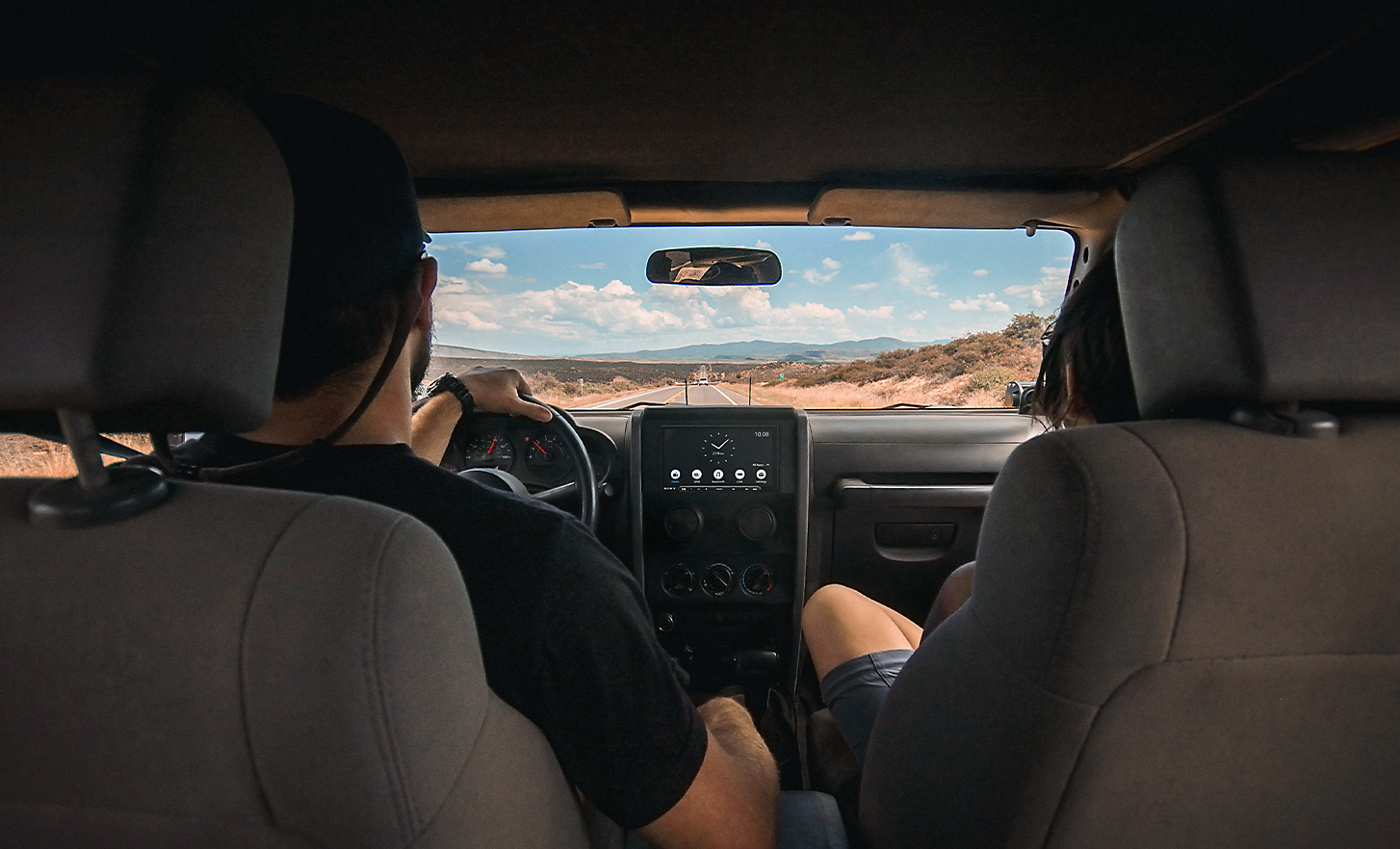 Image of two people driving through a desert-like environment with the XAV-AX6050 in the dashboard