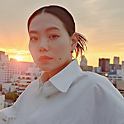 Image of a person on a rooftop with a sun setting over a city skyline in the background