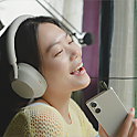 Image of a person listening to an Xperia 5 V with white headphones on and singing along to the music