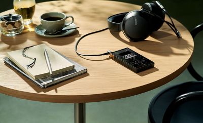 An image of the NW-ZX707 laying on a table, with Sony headphones.