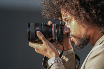 Obrázok osoby držiacej fotoaparát s pripevneným objektívom FE 50 mm F1,2 GM