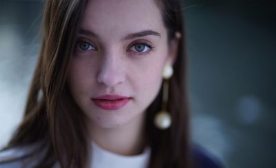 Close-up facial portrait of female model, with resolution of subject standing out against bokeh