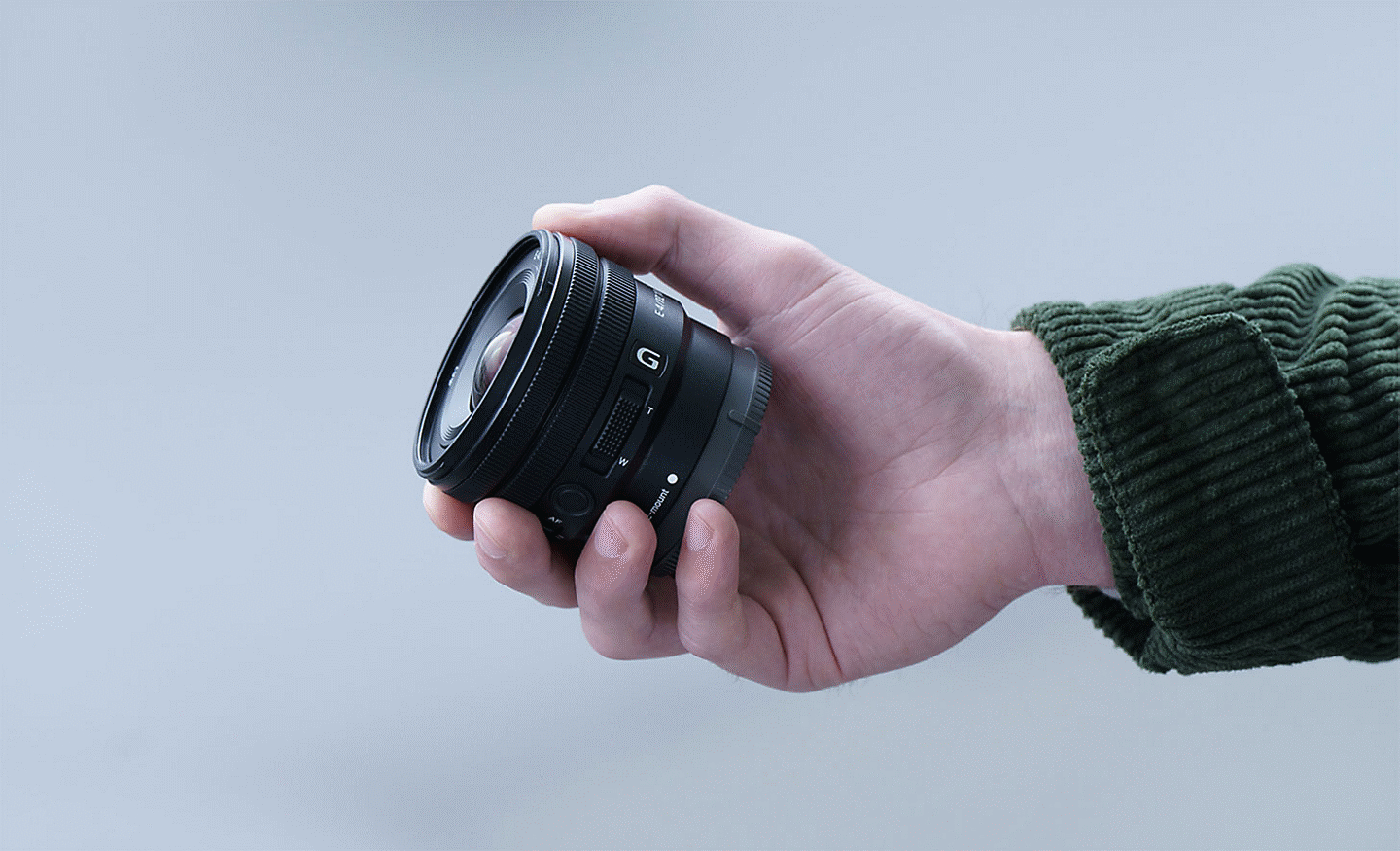Image of a person's hand holding the E PZ 10-20mm F4 G, showing that the lens is small enough to fit in their hand