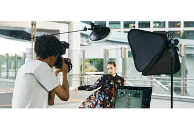 A man taking portrait a with flash connected via wireless radio communication with his laptop