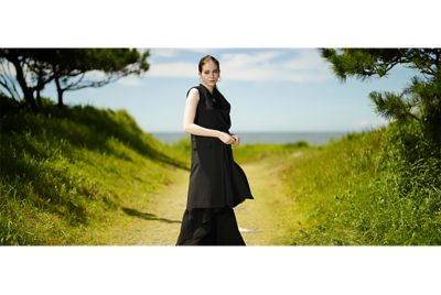 Image of a woman with beautiful bokeh, standing in a path to a beach