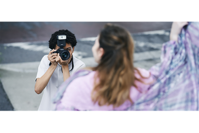 A man taking a snapshot outdoors with a model