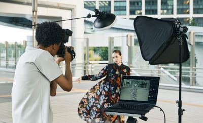 A man taking portrait a with flash connected via wireless radio communication with his laptop