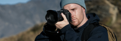 Användningsbild på en fotograf som håller i α7R VI utomhus.