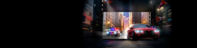 A red car followed by a police car drive out of a BRAVIA TV screen onto a city street