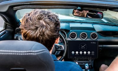 The XAV-AX8500 in position in a convertible car being driven by a smiling person