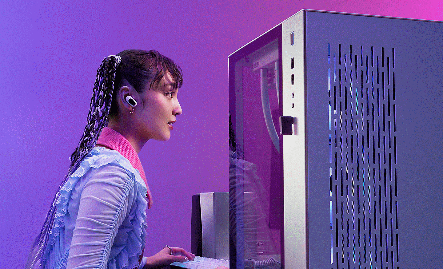 Imagem de uma gamer sentada junto a um monitor com os INZONE Buds nos ouvidos