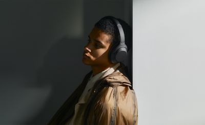 Bărbat relaxându-se în interior, cu o pereche de căști Sony WH-1000XM4C, modelul negru