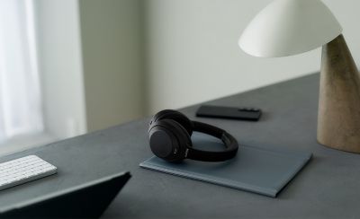 Căști Sony WH-1000XM4C, modelul negru, pe un birou minimalist acasă