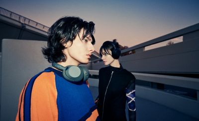 Two young people in an urban environment wearing the ULT WEAR headphones.