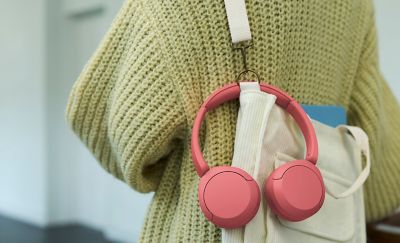 Sluchátka WH-CH530 korálové barvy visící na popruhu látkové tašky přes rameno